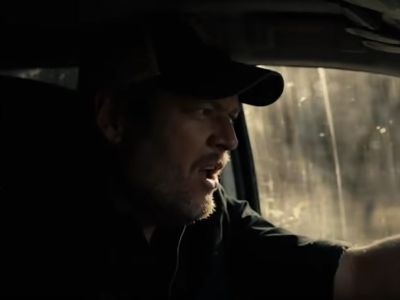 Blake Shelton is driving a car in the picture.